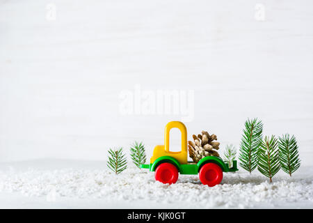 Ein kleines Spielzeug Auto ist ein Kran. Neues Jahr und Weihnachten Hintergrund. mini Weihnachtsbäume aus echten Fichte. santa claus aus Papier. Eine leere für ein postcar Stockfoto