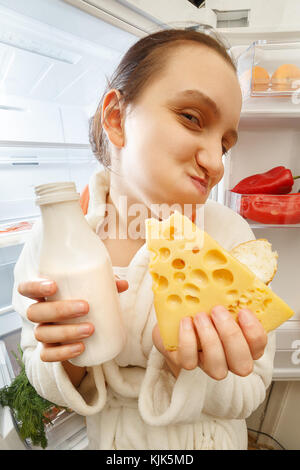 Hunger Frau Essen, das in der Nähe der Kühlschrank bei Kamera suchen Stockfoto