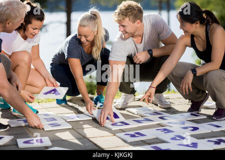 Männliche und weibliche Geschäft Leute lächeln während der Lösung Kreuzworträtsel auf der Terrasse im Wald Stockfoto