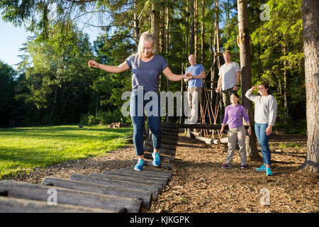 Multiethnischen friends junge Frau Kreuzung Brücke im Wald anmelden Stockfoto