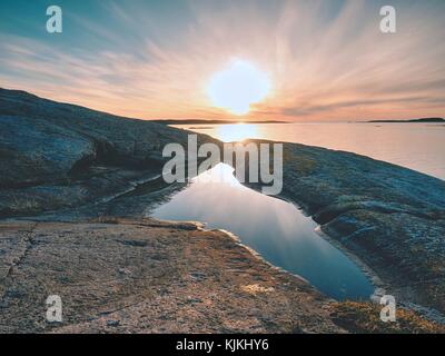 Konzept der seascape Sonnenuntergang bzw. Sonnenaufgang Hintergrund mit reichen Reflexion im Wasser Pool. Die Sonne ist das Hängen am Horizont in der Nähe von Meer oder Ozean Wasserstand, Stockfoto