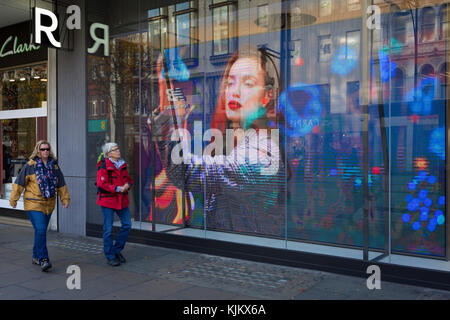 Pre-Christmas Käufer vorbei ein video ad-Schleife für die Londoner Händler 'Reserviert', auf der Oxford Street, am 23. November 2017 in London, England. Stockfoto