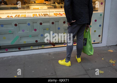 Ein Mann mit gelben Schuhe hält an Fenster Laden in Soho, am 22. November 2017 in London, England. Stockfoto