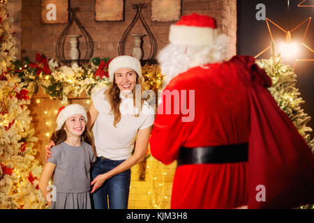 Santa Claus gibt ein Geschenk für ein Mädchen für Weihnachten im Zimmer. Stockfoto