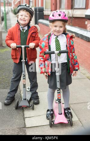 Zwei glückliche Kinder in ihrer Schule Uniformen gekleidet bereit zu roller zur Schule. Stockfoto