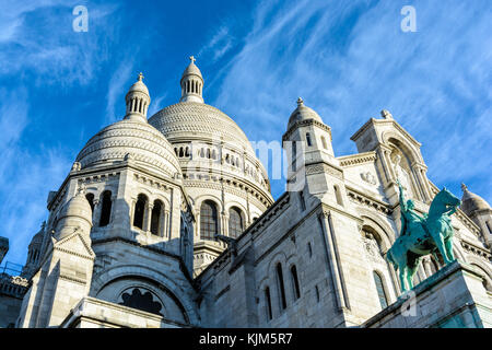 Drei Viertel der Blick von unten auf die Basilika des Heiligen Herzen von Paris mit einem Equestrian Bronze Statue im Vordergrund. Stockfoto