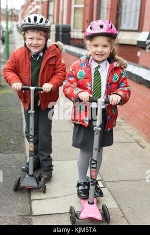 Zwei glückliche Kinder in ihrer Schule Uniformen gekleidet bereit zu roller zur Schule. Stockfoto