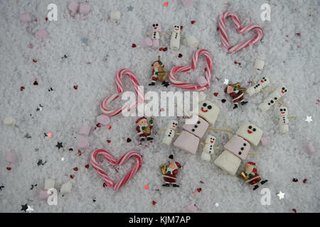 Weihnachten essen Fotografie Bild mit kleinen santa claus Dekorationen und Candy Cane liebe herz Formen im Schnee mit glücklichen Marshmallow Schneemann festgelegt Stockfoto