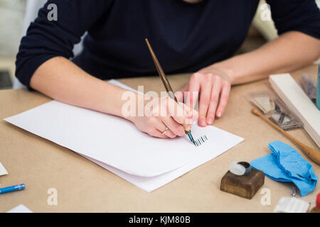 Kreativität, Kunst und Kunsthandwerk, Malerei cobcept. Nahaufnahme weiblichen Waffen professioneller Kalligraph, auf dem Blatt Sie schreiben mit Federkiel und schöne blaue Tinte Stockfoto