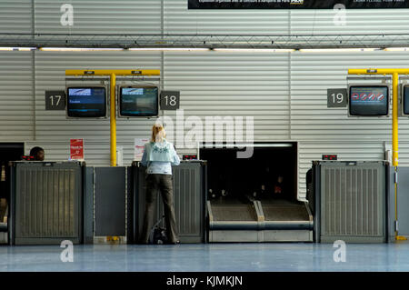 Eine Frau, die an einem Check-in-Schalter im Terminal 3 mit Handgepäck Stockfoto