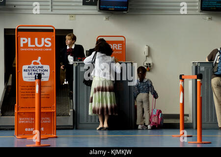 Freizeitaktivitäten Passagiere, eine Mutter und junges Mädchen am Terminal 3 easyJet Check-in-Schalter mit 'Keine tragen - auf Zeichen Gepäck Gewicht Einschränkungen" im Französischen lan Stockfoto