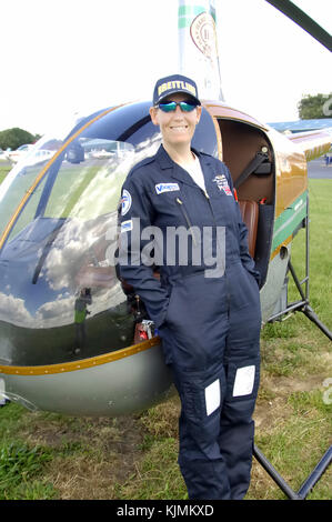 Caroline Gough Cooper, Hubschrauberpilot Champion in Großbritannien Frau bekleidet Flying-suit, Breitling Baseball Cap und Sonnenbrille neben ihr Robinson R-22 Stockfoto