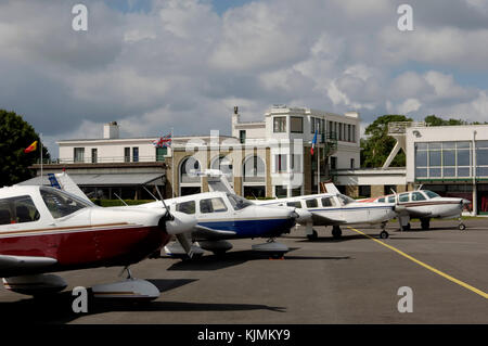 Reihe von leichten Flugzeugen, Piper Cherokee und eine Beech Bonanza auf Schürze mit Terminal Geparkt hinter Stockfoto