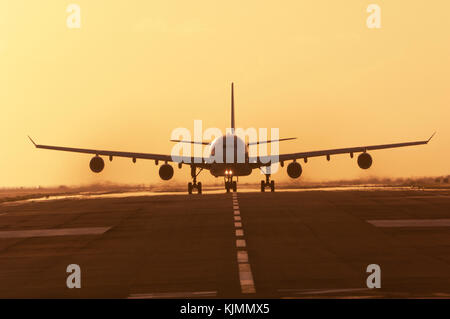 Ein Verkehrsflugzeug, die in der Abenddämmerung von der Start- und Landebahn am Flughafen, Sint Maarten in Niederländische Antillies. Rauchen Motoren. Stockfoto