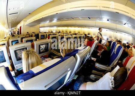 Passagiere in der Economy Class Sitze sitzen - beobachten das Inflight Entertainment auf einem Virgin Atlantic Airways Boeing 747-400 Fliegen enroute LHR Stockfoto