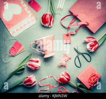 Stillleben mit Tulpen, rosa Schale, Shopping Bag, Geschenkbox, Schere und Papier Umschlag mit Herz, Ansicht von oben, flach Styling legen. Muttertag Gruß anhand von quantitativen Simulatio Stockfoto