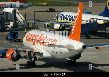 Eine easyJet Airbus A319-100 zurück geschoben werden mit einem Ryanair Boeing 737-800 und A319-100 an der South Terminal geparkt Stockfoto