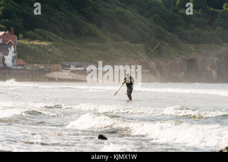 Ein Mann, der am Strand von Sandsend, whitby, großbritannien, angeln wird Stockfoto