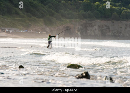 Ein Mann, der am Strand von Sandsend, whitby, großbritannien, angeln wird Stockfoto