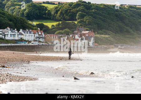 Ein Mann, der am Strand von Sandsend, whitby, großbritannien, angeln wird Stockfoto