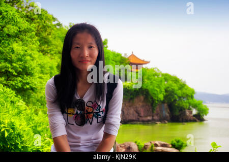 Eine chinesische Frau sitzt mit See tai oder taihu Unscharf im Hintergrund in Wuxi, China. Stockfoto