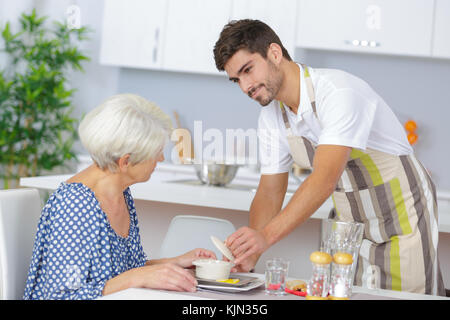 Pflegeperson, das Mittagessen zu den älteren Frau Stockfoto