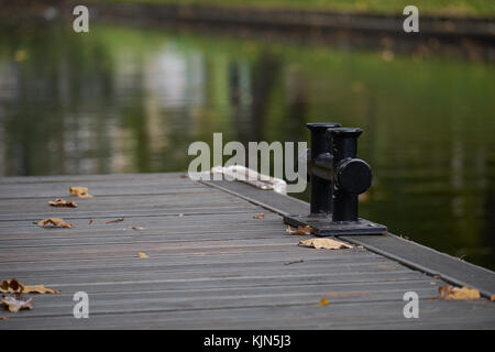 Black Metal Liegeplatz Poller auf einen Holzsteg an einem See mit Kopie Raum, Detail mit ausgewählten konzentrieren und enge Tiefenschärfe Stockfoto