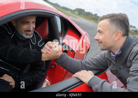 Sportwagen pilot Händeschütteln mit seinem Ingenieur auf Rennstrecke Stockfoto