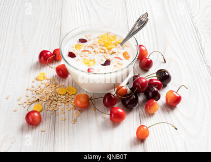 Schüssel mit hausgemachtem Joghurt mit Müsli und frischen Kirsche auf Holztisch. frischen Joghurt. gesunde Ernährung Konzept. hohe Auflösung Produkt. Stockfoto