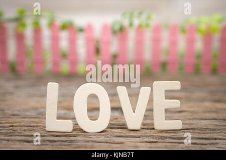 Liebe Wort und rosa Zaun auf Holz- Hintergrund mit Raum zu schreiben. Valentines Konzept, Vintage Tone, AF-Punkt ausgewählt. Stockfoto