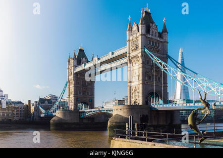 Gegenüberstellung von David Wynne Girl's Mit einem Delphin Statue in der Nähe der Tower Bridge in London - Victorian Engineering auf der Themse Stockfoto