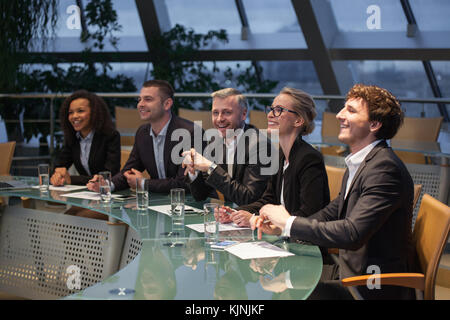 Eine Gruppe von Geschäftsleuten an einem Tisch sitzen zu diskutieren und zu lachen. Stockfoto