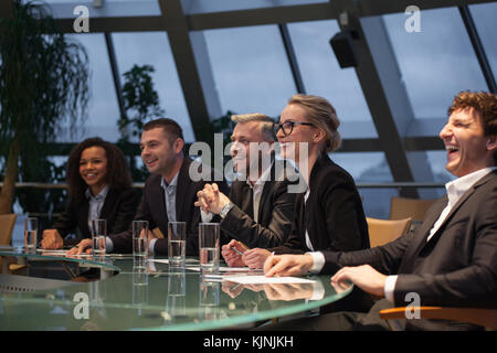 Eine Gruppe von Geschäftsleuten an einem Tisch sitzen zu diskutieren und zu lachen. Stockfoto