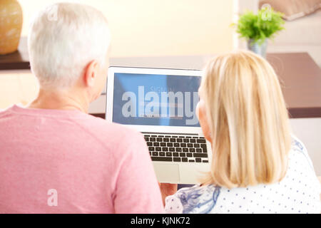 Ansicht von hinten erschossen von einem älteren Ehepaar banking online, während zu Hause sitzt und mit Laptop. Stockfoto