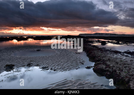 Eine stürmische Sonnenuntergang und Marine über compton Bay auf der Isle of Wight in der Nähe von Süßwasser. Niedrige schwarze Wolken mit bedrohlich und brütende Auftritt im Himmel. Stockfoto