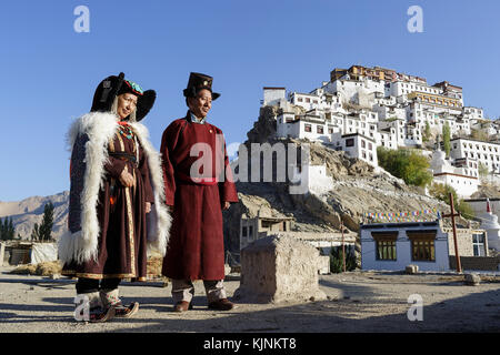 Eine ladakhi Paar tragen traditionelle Kostüme auf dem Dach Ihres Hauses, Thikse Kloster in der Rückseite, Leh, Ladakh, Jammu und Kaschmir, Indien. Stockfoto