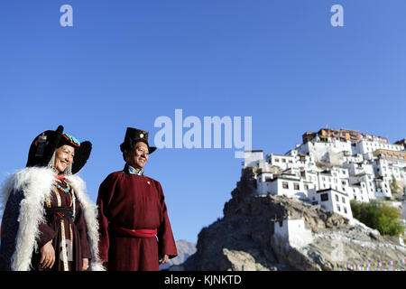 Eine ladakhi Paar tragen traditionelle Kostüme auf dem Dach Ihres Hauses, Thikse Kloster in der Rückseite, Leh, Ladakh, Jammu und Kaschmir, Indien. Stockfoto