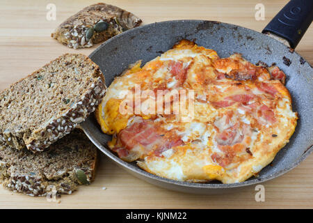 Starke Frühstück, gebratenen Speck und Eier in der Pfanne und gesunden chrono Brot mit Samen Stockfoto