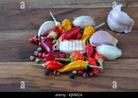 Scharfe Gewürze, Haufen von gemischten frischen Knoblauch, frisch und trocken Chili Paprika und rote, schwarze und weiße Pfefferkörner auf dunklem Hintergrund Stockfoto