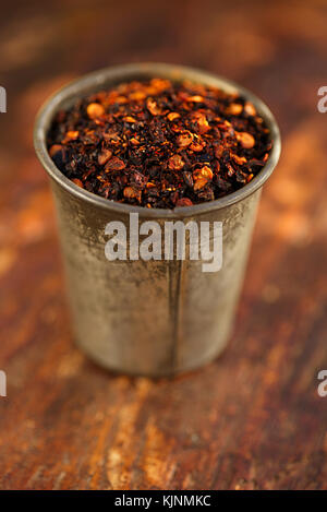 Chipotle jalapeno Geräuchertes chili Flocken in Vintage schimmel Zinn auf strukturierte woden Hintergrund Stockfoto