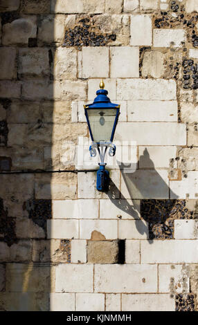 Alte blaue Metall Lampe wirft einen Schatten gegen eine Mauer aus Stein Stockfoto