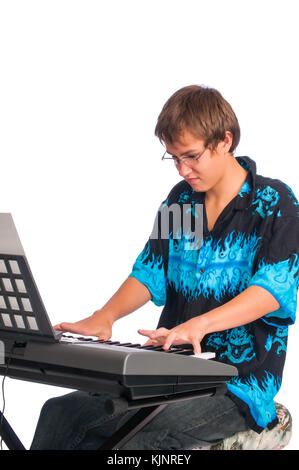 Ein Teenager an einer Tastatur spielen sitzt. Gegen einen weißen Hintergrund. Stockfoto