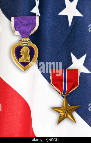 Us-Armee Bronze Star und Purple Heart Medaillen über eine Nahaufnahme auf eine amerikanische Flagge. Stockfoto