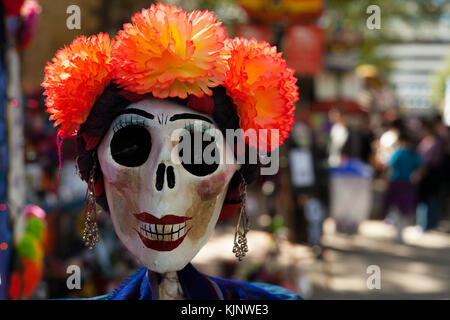 Schädel gemalt und mit orange Papiermache Blumen und Ohrringe/dekoriert Schädel für Dia de los Muertos, Tag der Toten eingerichtet Stockfoto
