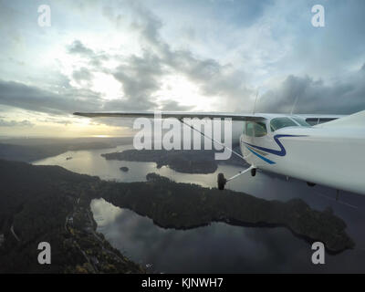 Kleines Flugzeug fliegt über die Stadt bei einem bewölkten Abend. in Vancouver, British Columbia, Kanada. Stockfoto