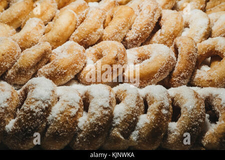 Reihen von frischen Donuts in Weißzucker, die für den Verkauf auf dem Markt kleine Stockfoto