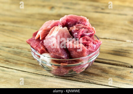 Auf die hölzerne Oberfläche ist ein Glas Vase. In der Vase liegt frisches Fleisch in Stücke geschnitten Stockfoto