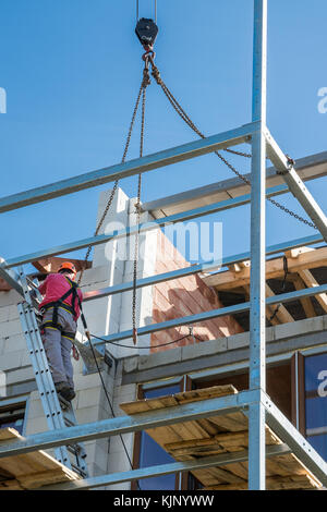 Höhe die Bauarbeiten unter blauem Himmel. Das Sichern der Arbeiter während der Montage Loggia. Stockfoto