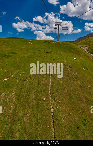 Seilbahn hoch in den Bergen des Kaukasus mit Grasebenen und Kuhweiden im Hintergrund Stockfoto