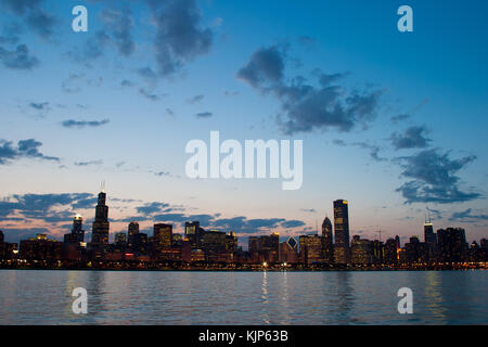 Ein warmer Frühling abends entlang des Lake Michigan Shore mit der berühmten Skyline von Chicago steigende über das ruhige Wasser. Stockfoto